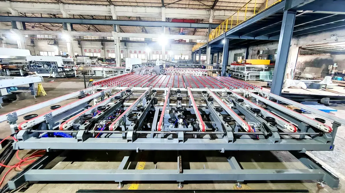 A wide-angle shot from the side showing the machine's extensive conveyor system with red rollers, positioned within a large, well-lit industrial warehouse.