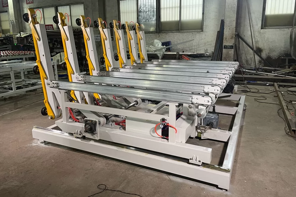A side-profile view of the loading machine, highlighting the robust white steel base and the series of yellow arms designed for lifting glass sheets.